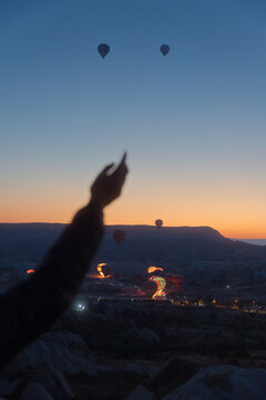 young woman stands against backdrop of rising hot air balloons