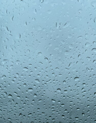 Macro abstract texture background of rain drops on a car window, with blue sky background