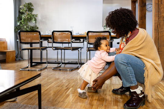 Cheerful crouching Mother and baby leaning on her at home living room - Powered by Adobe