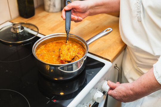 Senior woman preparing lentil soup at home kitchen