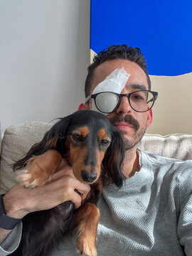 Man with Eye Patch and Dog on His Lap
