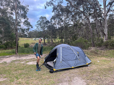 Man uses a pump to inflate an air mattress inside a tent in Australia