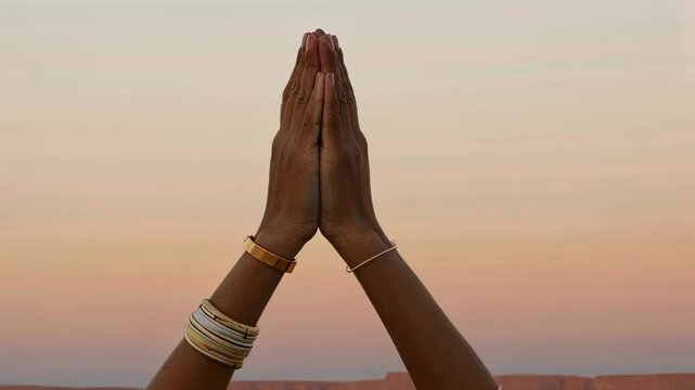 African American woman in prayer pose footage. Female hands in namaste mudra for meditation motion picture. Desert sunset background for yoga and mindfulness concept video.