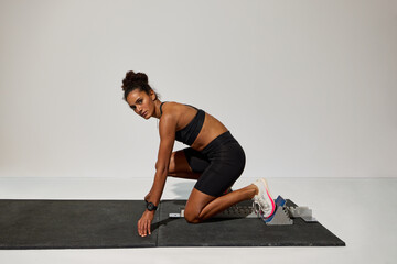 Female athlete prepares for workout while kneeling on mat