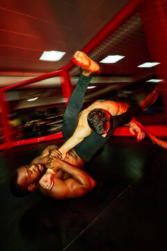 Intense grappling match in a training gym at night