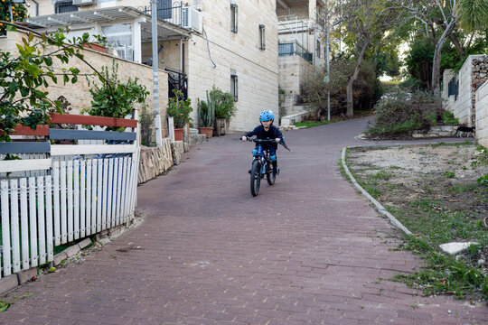 Child Riding a Bike with Full Safety Gear on a Quiet Street