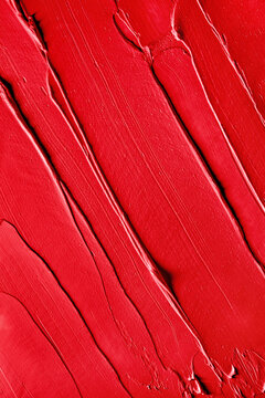 Layered textured background of red lipstick smeared on flat surface. 
