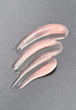 Pink lip gloss swatch smeared on silver background. 