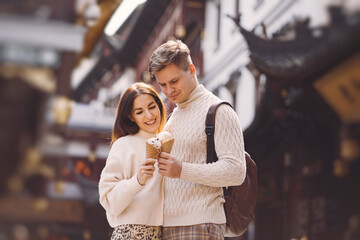 newlywed couple eating ice cream from a cone on a street in Shanghai near Yuyuan China.