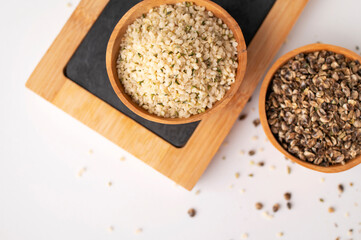 Hemp seeds in wooden bowls, kitchen writing board on light background, top view. Superfood, healthy...