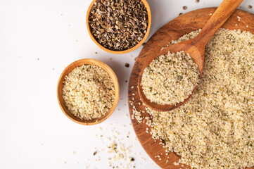 Hemp seeds in wooden spoon and bowls on light background, top view. Superfood, healthy tasty organic hemp seeds, source of omega 3 fatty acids, protein. Supplement to healthy diet