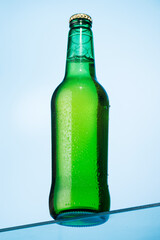 A cold beer bottle standing on a glass table