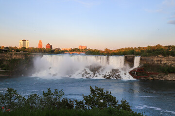 American Falls at golden hour with skyline of Niagara Falls, New York in background on June 3, 2019