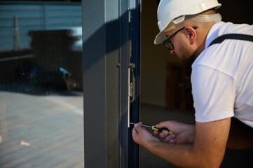 Construction worker installing door in a new house construction site. Man in working attire install...