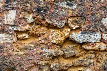 Rough texture of very old weathered stone wall with traces of time and cracks on surface. Texture background for design. Mason craft