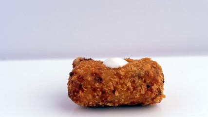 A vibrant image featuring a delicious fried croquette being held, capturing the crisp texture and culinary appeal. Perfect for illustrating food concepts, Spanish cuisine, or snacking experiences
