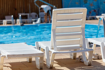 A white lounge chair is sitting in front of a pool