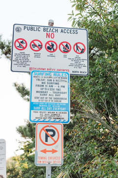 Beach access signs with rules listed for surfing and parking.