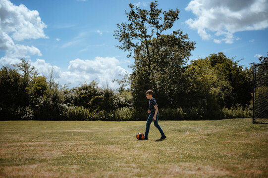 Boy kicking the soccer ball on the field.