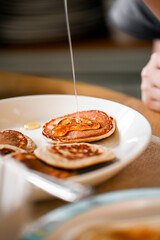 Close-up pouring honey over homemade pancakes, breakfast at home
