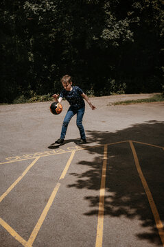 Boy playing with ball on the parking.
