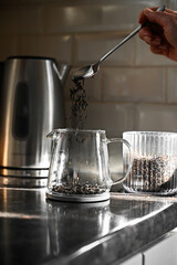 Pouring black tea leaves in a glass tea pot