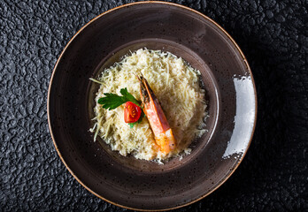 Creamy Shrimp Risotto in black plate on black background.