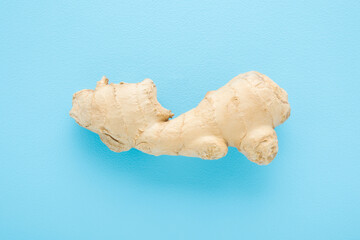 Fresh brown ginger root on light blue table background. Pastel color. Closeup. Top down view.