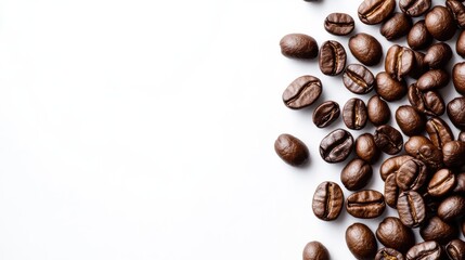 Obraz premium Freshly roasted coffee beans are scattered across a clean white surface. The rich brown tones and varied shapes of the beans emphasize their quality, perfect for brewing