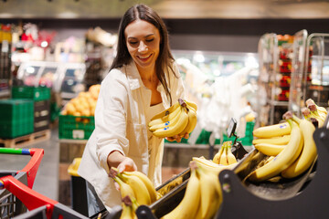 Smiling woman, happy customer choosing bananas in supermarket © Maria Vitkovska