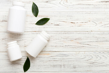 supplement pills with medicine bottle health care and medical top view. Vitamin tablets. Top view mockup bottle for pills and vitamins with green leaves, natural organic bio supplement, copy space