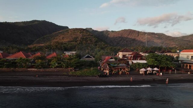 Drone view Picturesque amed beach showing black sand and lush green hills in bali, indonesia