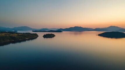 Obraz premium A breathtaking view of a tranquil lake at sunset, with soft colors reflecting on the water. Distant mountains provide a stunning backdrop for the peaceful landscape