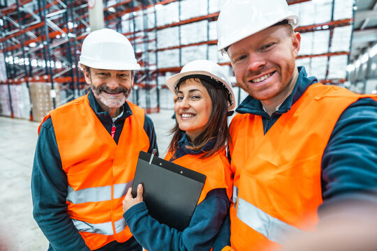 Warehouse workers smiling and taking selfie in logistics center