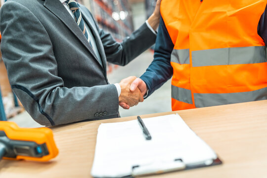 Manager and warehouse worker shaking hands after signing contract