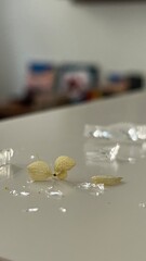 Delicate remnants of a flower on a smooth surface with scattered transparent materials in a softly lit room
