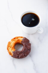 チョコレートでコーティングされたオールドファッションドーナツと、淹れたてのコーヒーで、おやつの時間
