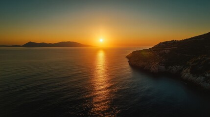 Obraz premium Breathtaking sunset over calm ocean with golden sky and distant hills