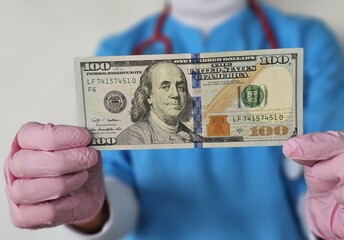 Doctor with US dollars hands. Concept of medical staff salary, money for medical exam or expensive health care concept