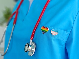 Woman doctor shows lgbt pride flag in her hand in hospital office. Medical support for lgbt...