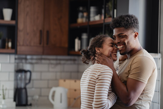 Happy couple sharing an affectionate moment in a modern kitchen, smiling and embracing with love and joy.