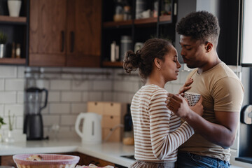 Young couple enjoying a lighthearted moment together in a cozy modern kitchen during breakfast time.
