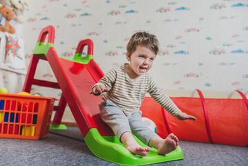 Baby slides down a slide, games in the nursery. Carefree childhood, children's centers and...