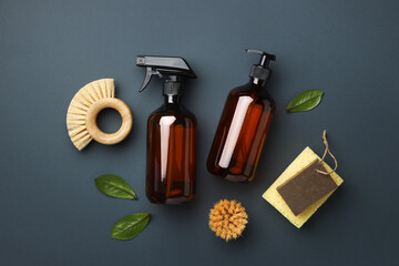 A spray bottle and dispenser with eco friendly cleaning brushes on grey background. Flat lay eco...