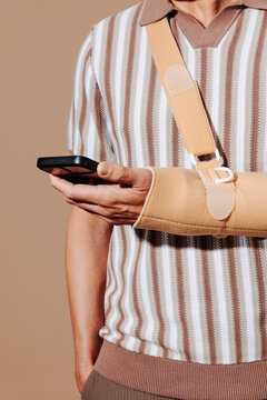 Man with tennis elbow wearing arm sling using smartphone