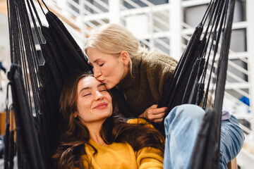 Mother kissing daughter in a hammock at home showing care and trust