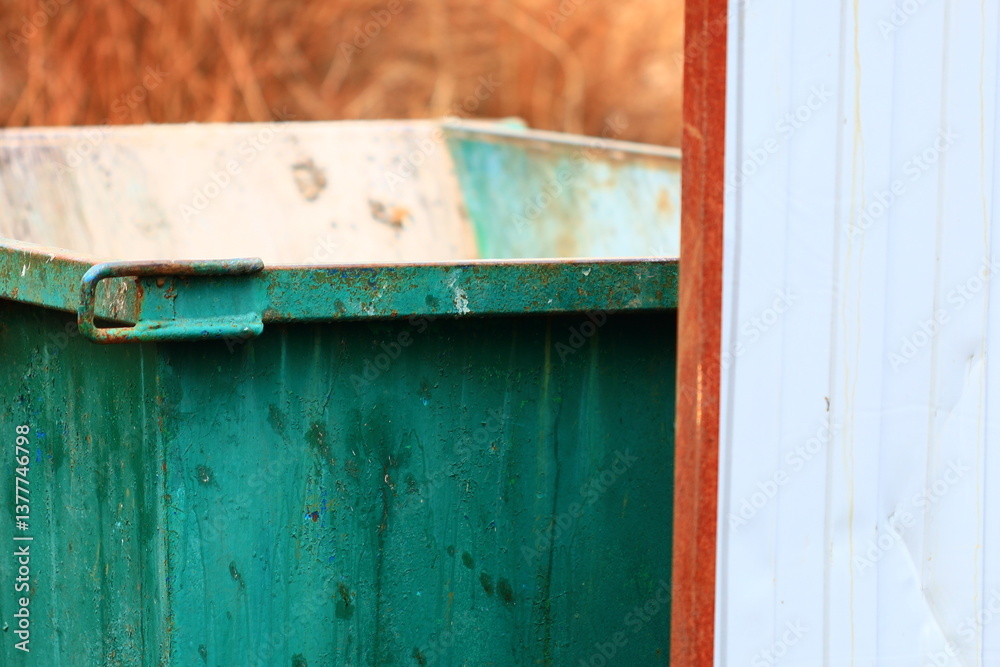 Poster a close-up shot of a small green trash can with a lid and handles.