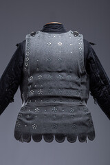 Gray Medieval Brigandine Armor with Leather Straps. This gray brigandine features overlapping metal plates riveted to a fabric base, secured with leather straps.