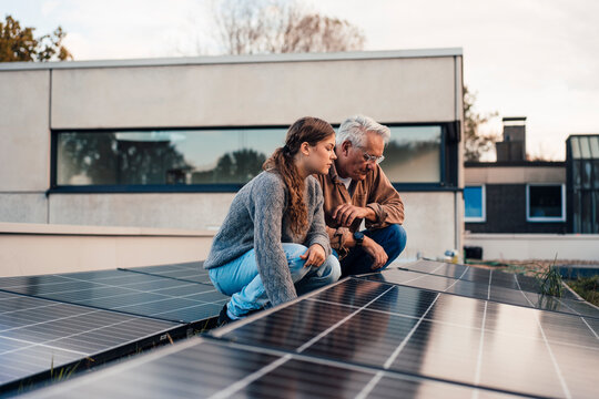 Grandfather and granddaughter examining solar panels outdoors
