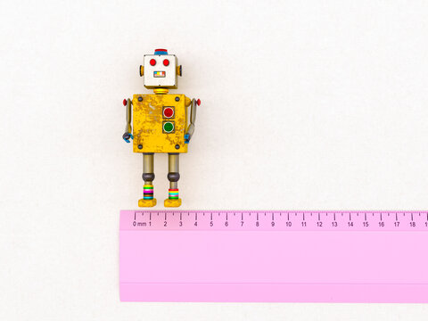 3D rendering of a colorful toy robot next to a pink ruler on a white background